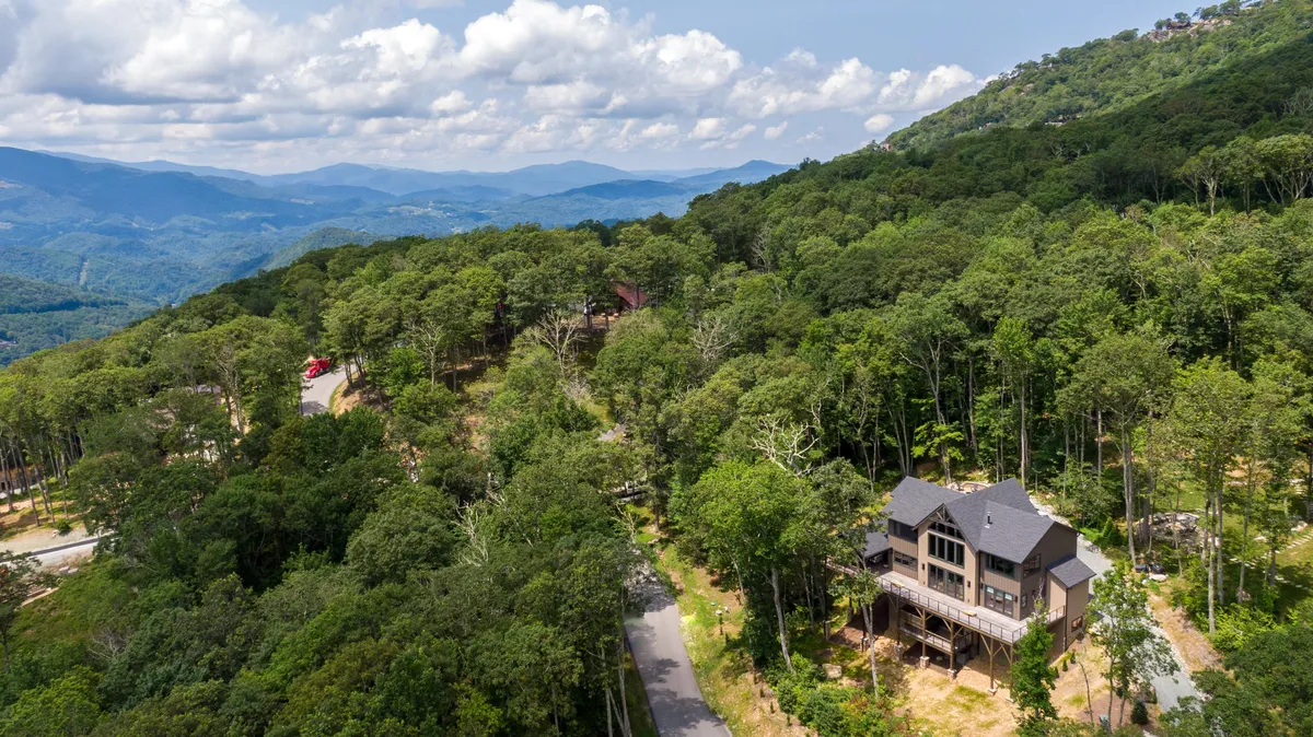 A tranquil shot of the house surrounded by trees with mountains in the distance, emphasizing proximity to hiking and nature exploration. The calm setting hints at early morning walks, scenic day trips, and the peacefulness that awaits after a day of adventure.