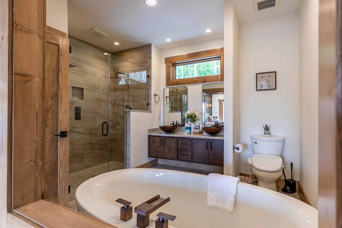 A spa-inspired bathroom with a freestanding bathtub, a walk-in shower, and a double vanity with mirrors, all set in a serene, well-lit environment. The design exudes modern luxury and relaxation.